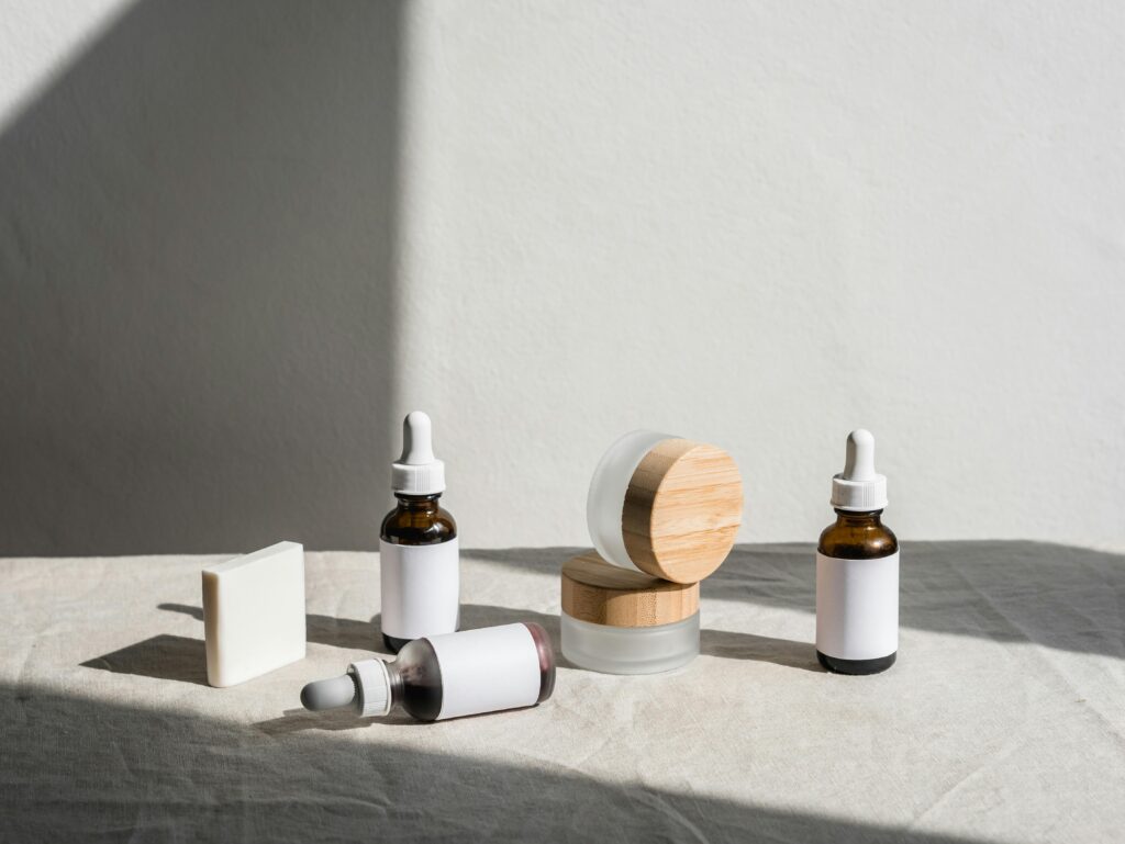 Flat lay of skincare products in jars and dropper bottles under soft natural light.